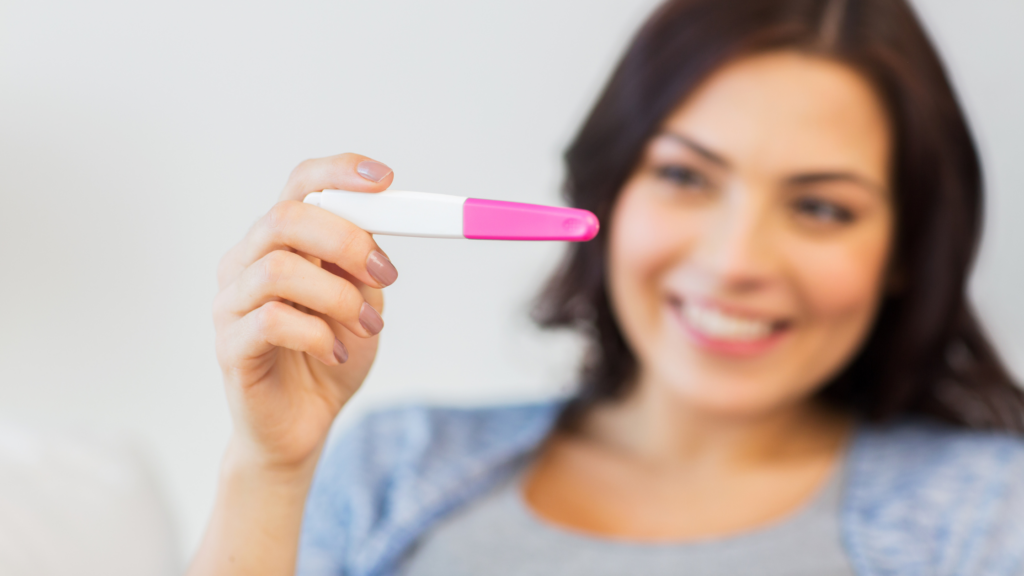woman looking at her pregnancy test happy she is pregnant 